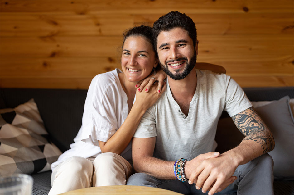 Portrait of a smiling boyfriend and girlfriend sitting on the sofa in their living room