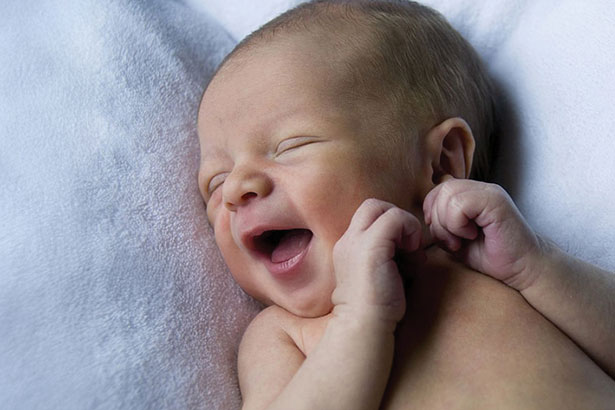 Infant smiling with eyes closed