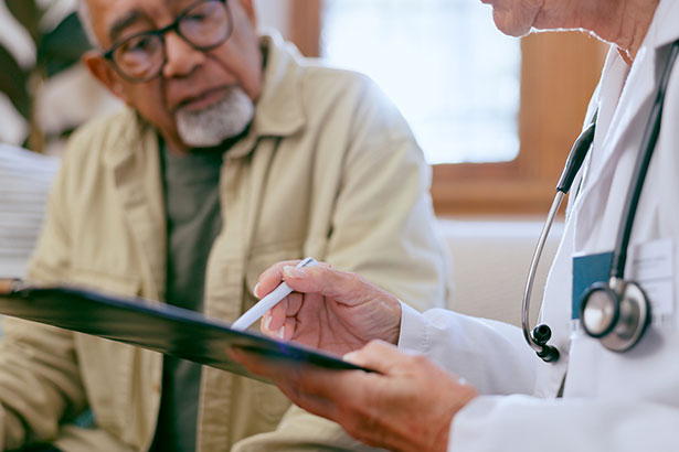 Senior man in discussion with doctor holding clipboard