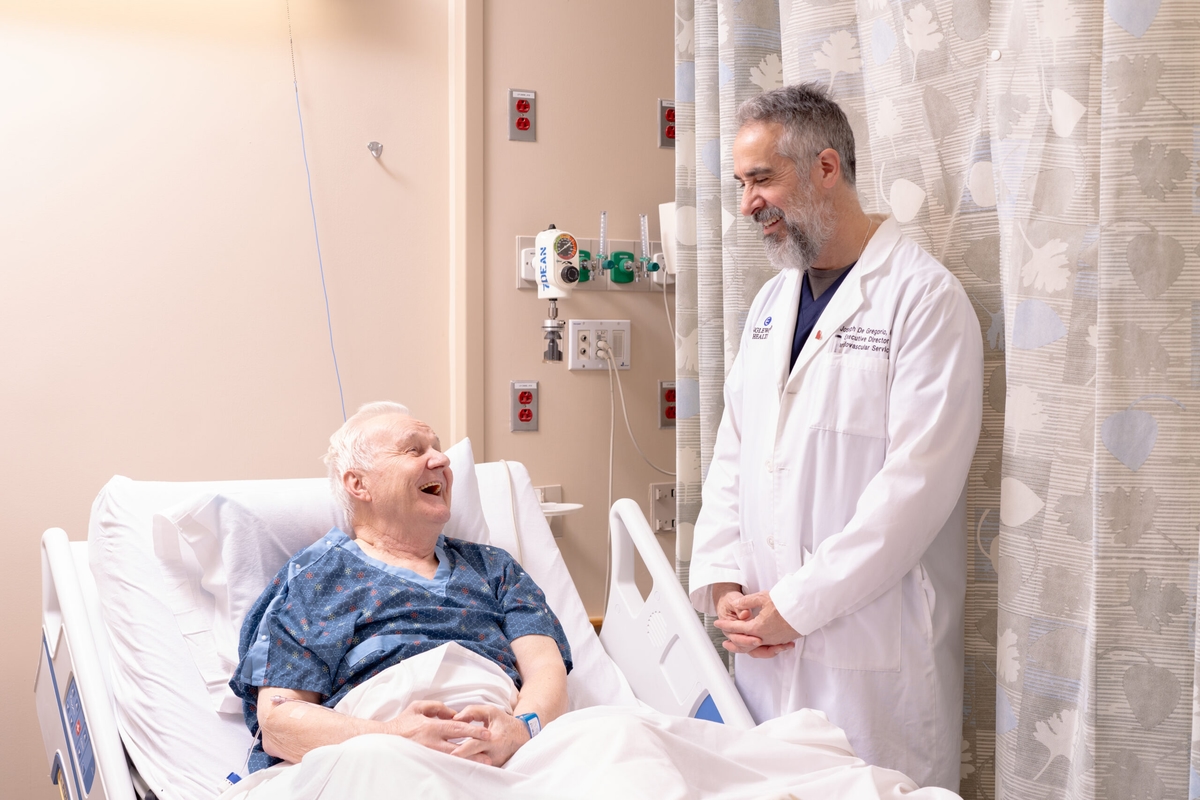 man in hospital bed speaking with the doctor who is at his bedside